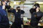 Sailors aboard the amphibious dock landing ship USS Pearl Harbor (LSD 52) don their gas masks during a general quarters drill.