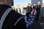 Sailors aboard the amphibious dock landing ship USS Whidbey Island (LSD 41) fold the American flag after arriving at Naples, Italy,