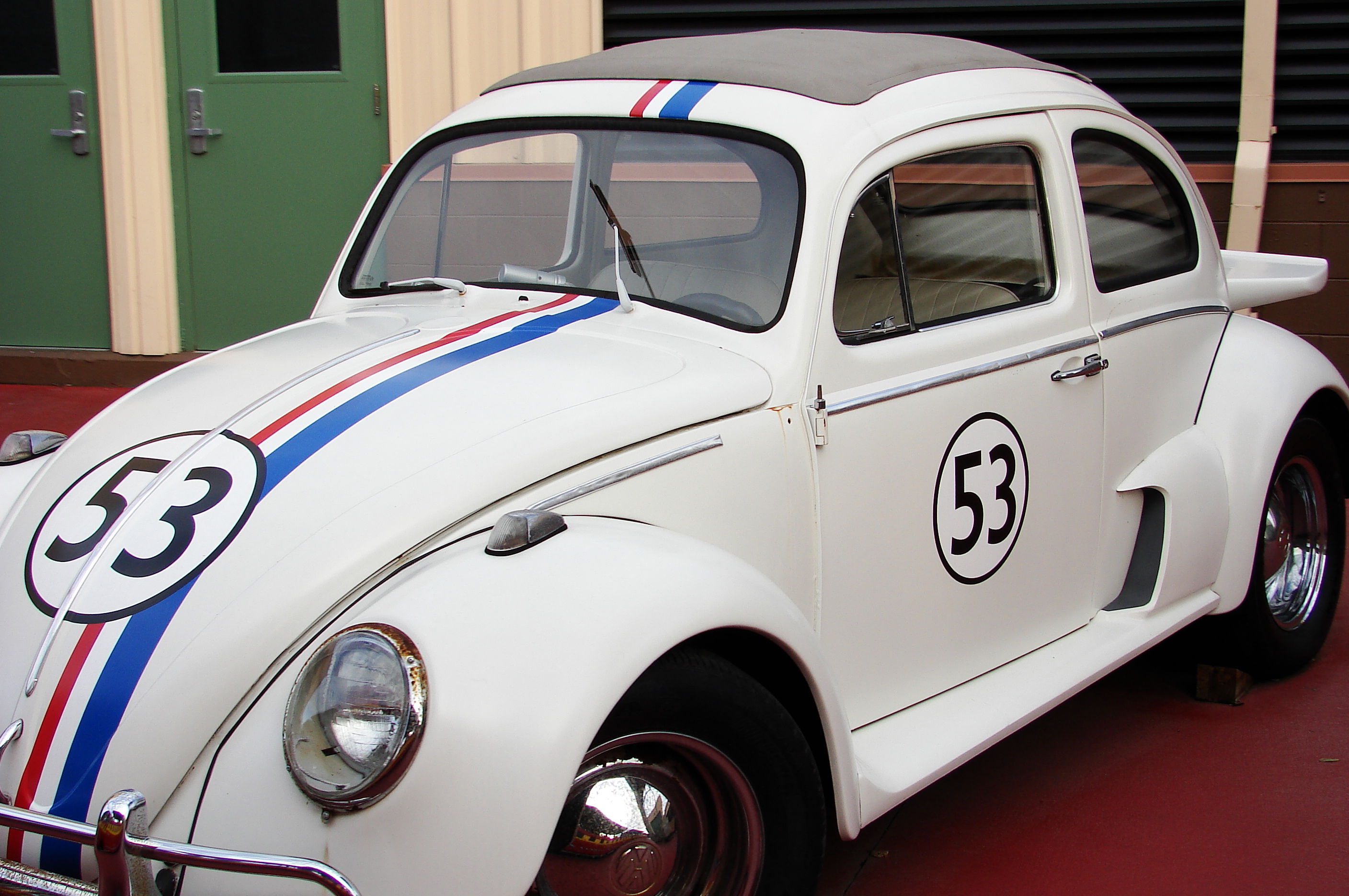 A white Volkswagen Beetle with a racing stripe across the middle and the number 53 on the front and the door