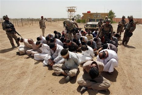 In this photo taken on Friday, July 20, 2012, blindfolded and handcuffed suspected al-Qaida members are guarded by Iraqi army soldiers in an Iraqi army base in Hillah, about 60 miles (95 kilometers) south of Baghdad, Iraq.