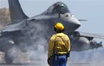 A crew member watches a Rafale fighter jet before being catapulted for a mission over Libya from France's flagship Charles de Gaulle aircraft carrier, in the Gulf of Sirte, off the Libyan coast, Wednesday, April 13, 2011. The missions are aimed at enforcing the no-fly zone and suppressing any attacks by Gadhafi's forces against civilians and rebels in eastern Libya.