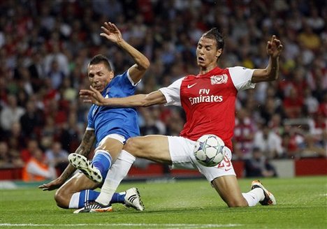 Arsenal's Marouane Chamakh, right, tackles Olympiakos' Jose Holebas