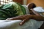 File - HIV/AIDS patient lies in bed at the Bairo Pite clinic for comprehensive community health service, Dili, East Timor.