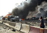 In this photo released by the Syrian official news agency SANA, a Syria man, right reacts as flames and smoke rise from burned cars after two bombs exploded, at Qazaz neighborhood in Damascus, Syria, on Thursday May 10, 2012.