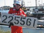 CRESCENT CITY, Calif. - Petty Officer 1st Class Brian Higgins, a marine science technician of Coast Guard Sector San Francisco, holds the fishing vessel Kodiaks I.D. number, Tuesday, April 5, 2011, after it was recovered for the vessel owner. The 67-foot wooden vessel, known for performing rescue missions in Alaska, sank during the March 11, 2011, tsunami. Photo by Carol Singleton, California Department of Fish and Game. (1193168) ( Crescent City pollution response )