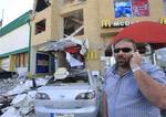 In this picture taken on Monday, April 23, 2012, Lebanese Zahi Zaidan who runs a restaurant serving alcohol which was attacked by bomb, speaks on his phone at the bombed scene, in the southern port city of Tyre, Lebanon. A wave of bombings targeting liquor stores and restaurants serving alcohol in this southern port city over the past six months have scared some while others are defiant and continuing with their work as usual despite the dangers.