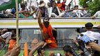 Indian yoga guru Baba Ramdev waves out of the window of a bus after he was detained with his supporters by policemen in Delhi, India. 