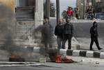 Anti-Syrian government protesters, stand next to burning tires as they protest in the southern city of Daraa, Syria, Wednesday March 23, 2011. Syrian security forces shot live ammunition and tear gas early Wednesday near a mosque where protesters have been camped out in southern Syria, killing six people including a paramedic, activists said. The early morning attack near the al-Omari mosque in the southern city of Daraa marks the deadliest single day since anti-government protests inspired by u