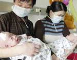 Parents hold twin sisters Sunday at the First Hospital of Hebei Medical College. The hospital separated the girls who were conjoined at the chest and belly on February 14. The infants are in stable condition and each drinks up to 400 ml of milk each day.