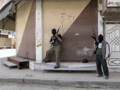 In this Friday, April 6, 2012 photo, Free Syrian Army fighters stand guard during fighting with Syrian troops in a suburb of Damascus, Syria.