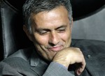 Real Madrid coach Jose Mourinho, of Portugal, smiles as he sits on the bench during a Champions League, group G soccer match between AC Milan and Real Madrid at the San Siro stadium in Milan, Italy, Wednesday, Nov. 3, 2010.