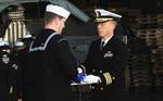 Cmdr. Stevin Johnson passes the flag to Religious Programs Specialist 3rd Class Daniel Graham during a burial at sea ceremony aboard the Nimitz-class aircraft carrier USS John C. Stennis (CVN 74).