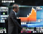 A man walks past an electronic stock board in downtown Tokyo Friday, Nov. 21, 2008. The benchmark Nikkei 225 stock average gained 207.75 points, or 2.7 percent, to close at 7,910.79 points on the Tokyo Stock Exchange, after losing nearly 7 percent the day before.