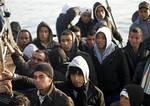 Migrants are seen aboard a boat as they reach the Sicilian island of Lampedusa, Italy, early Monday, March 7, 2011. More than 1,000 migrants from North Africa have arrived in Italy overnight, some in rickety boats that had to be escorted ashore by the Italian coast guard.