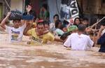 Residents hang on to a rope as they pass strong currents along a flooded area in Marikina, east of Manila, Philippines on Thursday Aug. 9, 2012.