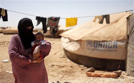 Syrian refugee, Omm Ahmed, from Daraa, Syria, carries her newly-born infant near her tent, at Zaatari Refugee Camp, in Mafraq, Jordan, Sunday, Sept. 2, 2012.