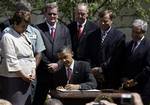 President Barack Obama signs a presidential memorandum outlining the next steps of cleaner and more efficient vehicles during and event in the Rose Garden at the White House in Washington, Friday, May 21, 2010. At left is Lisa Jackson, EPA administrator.