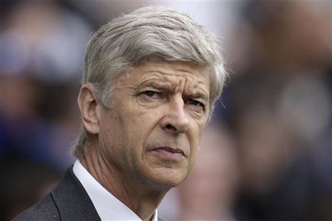 Arsenal's manager Arsene Wenger looks on from the dugout before the start of their English Premier League soccer match against Queens Park Rangers at Loftus Road stadium, London, Saturday, March 31, 2012.