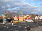 Looking northeast across Jamaica Avenue at south end of Queens Boulevard on a mostly cloudy afternoon.