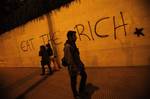 Pedestrians pass by graffiti on wall during a protest against austerity measures in Athens on Thursday, Nov. 17, 2011.