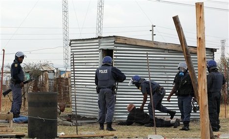 Police officers round up a group of men as they patrol the area near the Lonmin Platinum Mine near Rustenburg, South Africa, Saturday, Sept. 15, 2012.