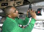 Aviation Structural Mechanic 2nd Class Kelvin Santos of Bronx, New York replaces rivets on the tail hook hydraulic system of an F/A-18B Hornet .