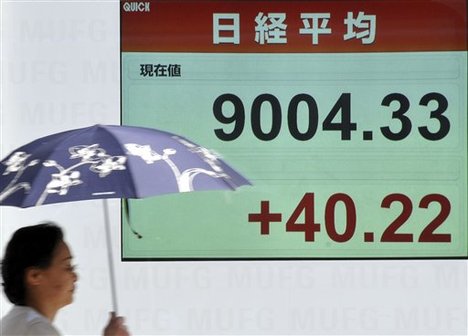 A woman walks by an electric market board in Tokyo indicating Japan's Nikkei 225 stock average added 40.22 points to 9,004.33, clearing the 9,000 point level at one point in the afternoon, Monday, April 13, 2009.