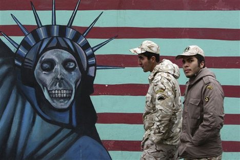 Soldiers of the Iranian Revolutionary Guard walk past a satirical drawing of Statue of Liberty on the wall of the former US Embassy in Tehran, Iran, Friday, Nov. 25, 2011.