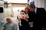 President George W. Bush reads a baby book with U.S. Army Reservist First Lieutenant Brandan Mueller of Webster Groves, Mo., his wife Amanda, and their daughter Abigail at Walter Reed Army Medical Center in Washington, D.C., Friday, March 19, 2004. Lt. M