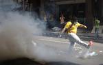 A protester kicks away a tear gas canister fired by Malaysian police during a rally to demand for electoral reforms in Kuala Lumpur, Malaysia, Saturday, April 28, 2012. Police unleashed tear gas and chemical-laced water Saturday at thousands of demonstrators who staged one of Malaysia's largest street rallies in years, demanding fair rules for national elections expected soon. (AP Photo/Lai Seng Sin)