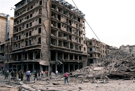 In this photo released by the Syrian official news agency SANA, Syrian security officers gather at the scene in front of destroyed buildings where triple bombs exploded at the Saadallah al-Jabri square, in Aleppo city, Syria, Wednesday Oct. 3, 2012.