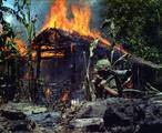 Vietnam. A Viet Cong base camp being burned down. In the foreground is Private First Class Raymond Rumpa, St Paul, Minnesota, C Company, 3rd Battalion, 47th Infantry, 9th Infantry Division, with 45 pound 90 mm recoiless rifle