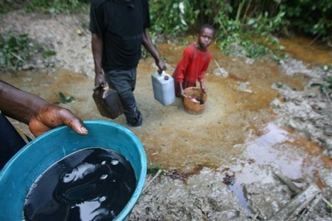 Locals collect oil from an oil polluted stream in Oshie near Port Harcourt, Nigeria, Tuesday, Oct. 31 2006.