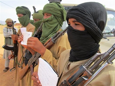 In this Thursday, Sept. 27, 2012 photo, young fighters, including 13-year-old Abdullahi, right, and 14-year-old Hamadi, second right, display their Quranic studies notes for a journalist as their Islamist commanders look on, in Douentza, Mali.