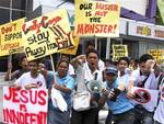 Members of a religious group give thumbs-down signs as they shout 