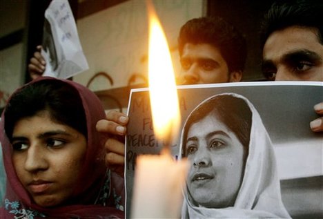 Pakistani men hold pictures of 14-year-old schoolgirl Malala Yousufzai, who was shot last Tuesday by the Taliban for speaking out in support of education for women, during a candlelight vigil in Karachi, Pakistan, Saturday, Oct. 13, 2012.