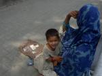 Kashmiri beggar woman with her daughter sit infront of closed shops during a one day strike, to commemorate the killing of dozens of local youth in alleged police actions during the 2008-2010 civilian unrest, called by hardline separatist leader Syed Ali Shah Geelani in Srinagar on June 11,2012.