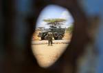 SOMALIA, Kismayo: In a handout photograph taken 05 October and released by the African Union-United Nations Information Support Team 06 October, a soldier serving with the Kenyan Contingent of the African Union Mission in Somalia (AMISOM) is seen standing infront of an armoured personnel carrier through a bullet hole in the gate the former compound housing the offices of the United Nations High Commission for Refugees (UNHCR) while a combat engineering team sweeps the area for unexploded ordinac