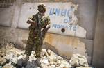 SOMALIA, Kismayo: In a handout photograph taken 05 October and released by the African Union-United Nations Information Support Team 06 October, a soldier serving with the Kenyan Contingent of the African Union Mission in Somalia (AMISOM) stands guard infront of the former compound housing the offices of the United Nations High Commission for Refugees (UNHCR) while a combat engineering team sweeps the area for unexploded ordinace and improvised explosive devices (IEDs) in the southern Somali por