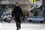 Plain clothed police officers, right rear, prepare for a controlled blast at a private delivery company in Athens, Tuesday, Nov. 2, 2010. Greek police say small parcel bombs exploded at the Swiss and Russian embassies in Athens, and suspicious packages were detonated outside Parliament, the Bulgarian embassy and a courier company.