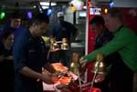 Capt. Kent D. Whalen, the commanding officer aboard the Nimitz-class aircraft carrier USS Carl Vinson (CVN 70), serves Machinist's Mate 1st Class Jose Barraza and other Sailors Christmas dinner on the mess decks.