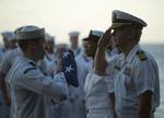 Capt. Kent D. Whalen, commanding officer of the Nimitz-class aircraft carrier USS Carl Vinson (CVN 70), renders honors as Aviation Ordnanceman Airman Nathan Rings presents him with the national ensign.