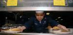 Culinary Specialist 1st Class Nino O. Villamor, displays two sample plates in the main galley serving line aboard amphibious assault ship USS Bonhomme Richard (LHD 6) (BHR).