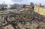 Thousands of Egyptian protesters gather at Tahrir square in Cairo, Egypt, Sunday, Jan. 30, 2011, with the ruling National Democratic party building burned at centre left behind the red coloured Egypt museum.