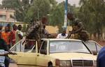 Two soldiers loyal to junta chief Capt. Amadou Sanogo load their weapons, including a machine gun, onto a taxi which they hailed while returning on foot from the parachutists military camp, where junta soldiers took control in fighting against anti-junta forces, in Bamako, Mali, Tuesday, May 1, 2012. Gunfire echoed across the capital Tuesday as Malian government troops battled each other, killing at least 12 people as one side tried to oust soldiers who seized power in a coup over a month ago. M