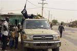 In this Saturday, April 14, 2012 photo, fighters from the Ansar Dine group, flying the group's black flag, instruct local residents in how to follow Shariah, as they stop in a market area of Timbuktu, Mali. West Africa's regional bloc is recommending the deployment of a regional force to Mali after Tuareg rebels declared an independent state, dubbed Azawad, following a military coup last month. The fighters are divided between a secular group and an Islamist faction that wants to impose Shariah