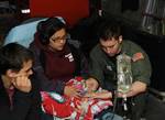 KODIAK, Alaska - Coast Guard Petty Officer 3rd Class David Call, a health services technician with Rockmore-King Clinic and resident of Ridgefield, Wash., counts a 5-month-old girl's breath respirations during a medevac aboard an HC-130 Hercules aircraft April 7, 2011. Call would count how many times she would breathe in one minute as well as document her other vital signs 15 minutes to ensure the patient was stable and her oxygen level did not drop during the flight from Cold Bay to Anchorage.