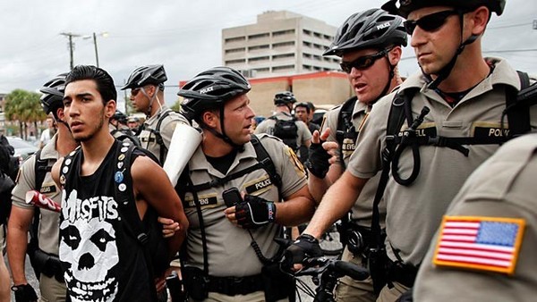 (A photograph of a huge crowd of bicycle cops arresting a young man in a Misfits t-shirt, while other bike cops hold onlookers off at a distance.)