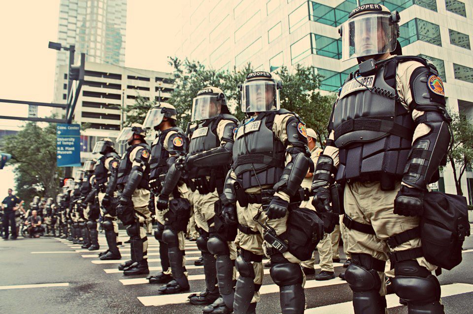 (A photograph of a line of State Troopers in heavy body armor and riot gear.)