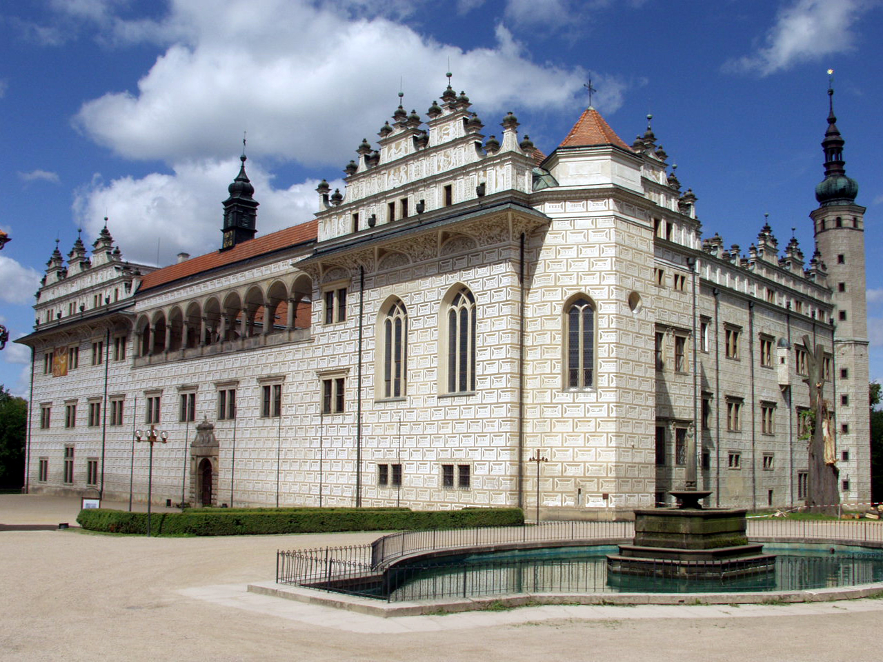 Large rectangular building of pale stonework, multiple rectangular windows and ornamental features at the roof level